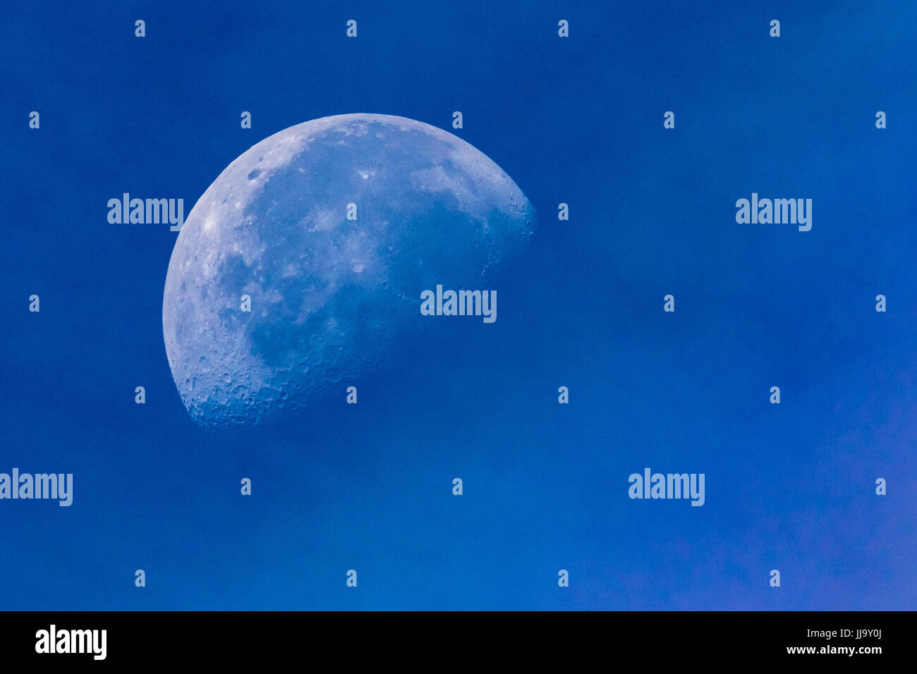 Foto orizzontale della luna contro un giorno Blu Cielo e nubi di luce in primo piano Foto Stock