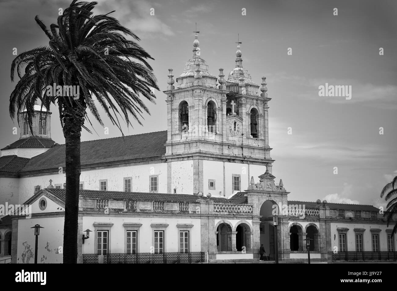 Foto di una chiesa e di un albero di palma durante una giornata di vento Foto Stock