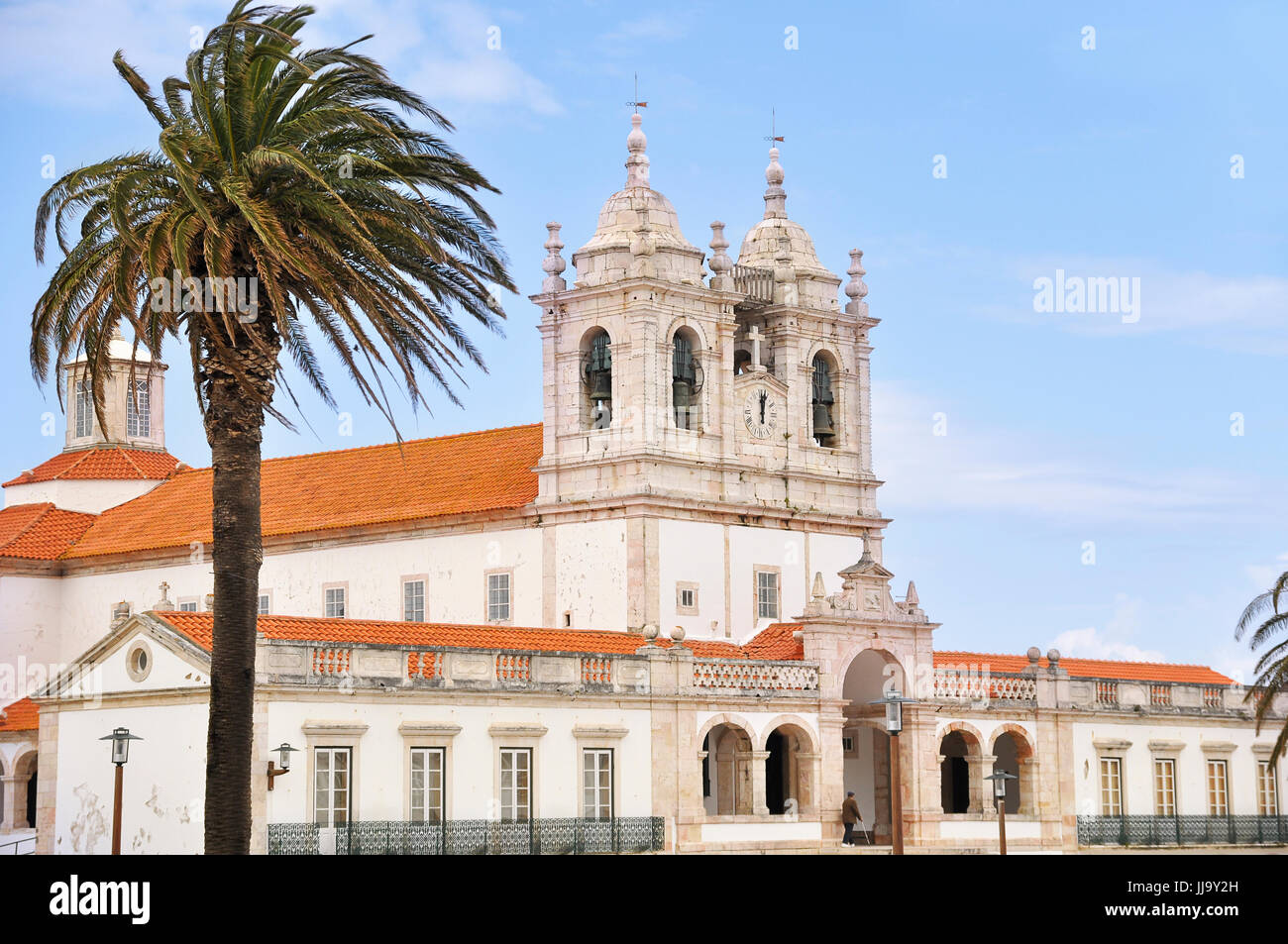 Foto di una chiesa e di un albero di palma durante una giornata di vento Foto Stock