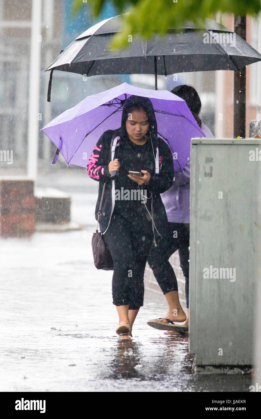 Una donna cammina attraverso allagamenti acqua sul suo modo home dopo forti piogge ha causato allagamenti per la A525 in estate durante il tuono e le tempeste di fulmini che ha colpito la zona, Rhyl, Galles del Nord, Regno Unito Foto Stock