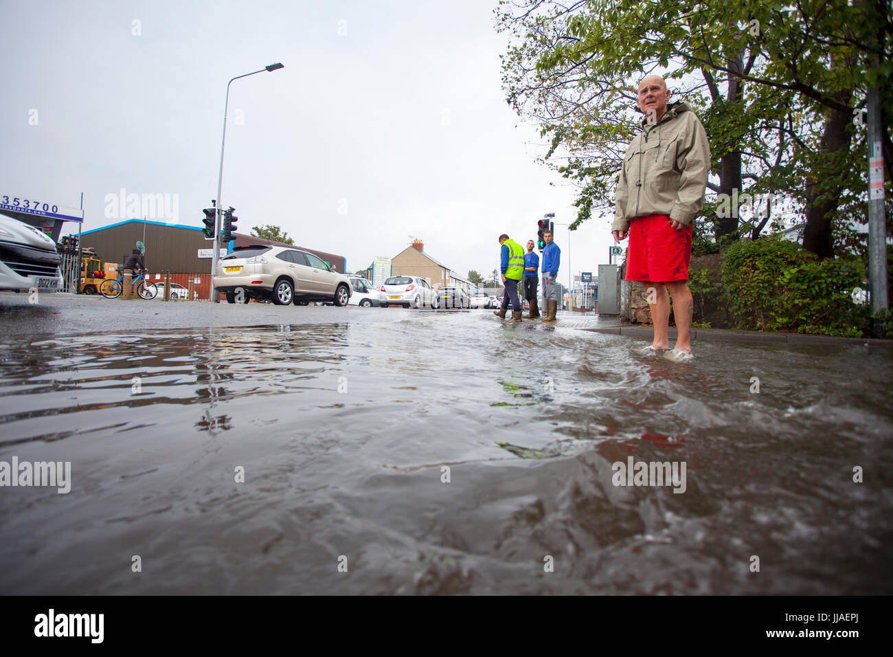 Persone catturati fuori dalle piogge torrenziali e inondazioni flash durante un temporale estivo in quanto a piedi attraverso strade allagate sulla A525 strada in località costiera città di Rhyl, Denbighshire, Wales, Regno Unito Foto Stock