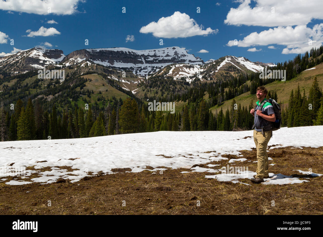 Un maschio di escursionista in piedi su Phillips passano nel Teton Mountains, ancora coperte di neve. Jedediah Smith Wilderness, Wyoming Foto Stock