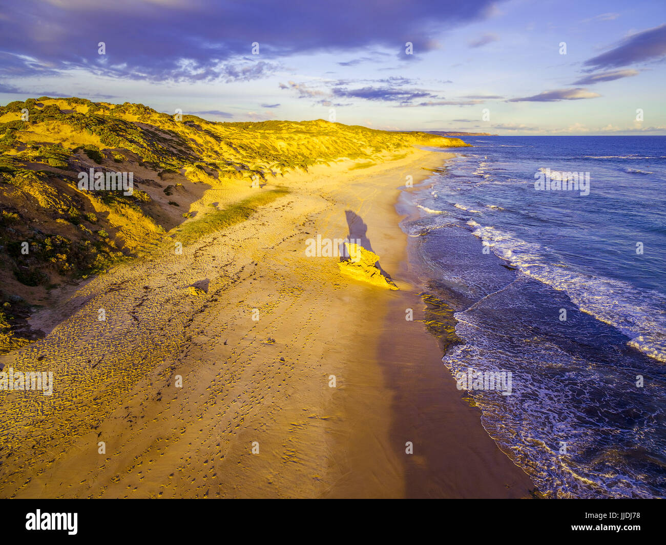 Roccia calcarea e la formazione con una lunga ombra sulla spiaggia dell'oceano incandescente al tramonto Foto Stock