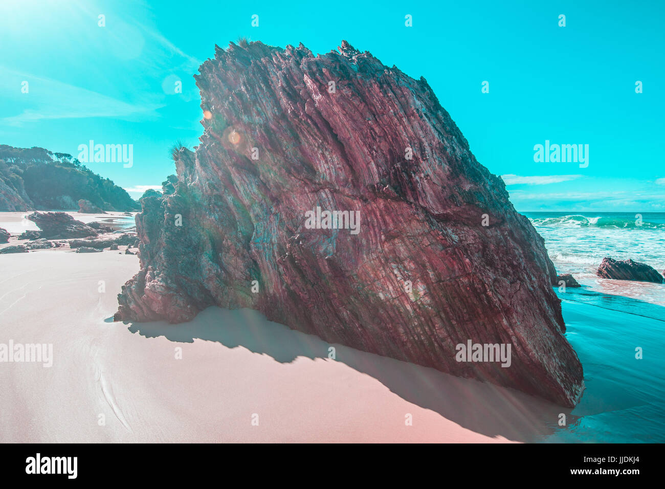 Weathered roccia calcarea formazione sulla sabbiosa spiaggia oceano a mezzogiorno la colata ombre lunghe con sun flare e spazio di copia Foto Stock