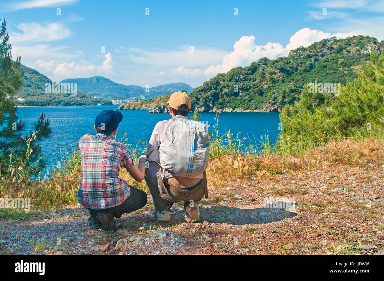 Caucasian figlio adolescente in maglietta controllato ed il tappo con il suo padre guardando alla baia di Marmaris con vista mare e montagne a sfondo sulla giornata di sole, Turchia Foto Stock