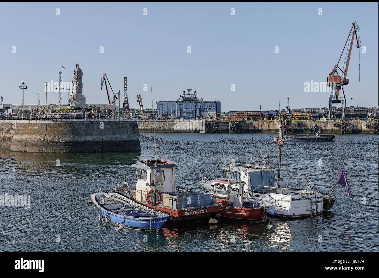 Porto di pesca e una statua della Vergine del Carmen in scogliera in fondo al villaggio di Santurtzi, Bilbao, Vizcaya, Paesi Baschi Foto Stock