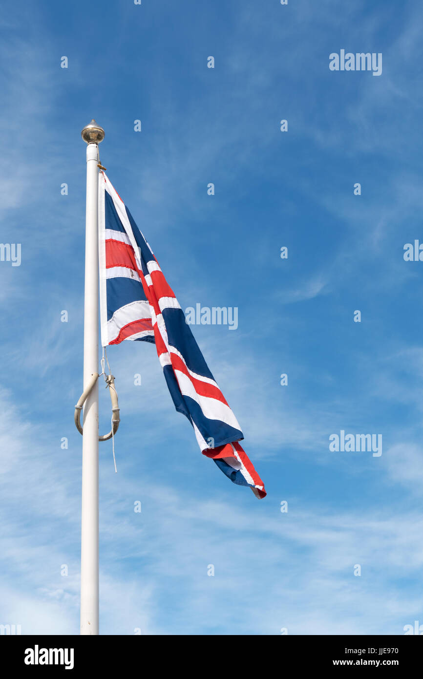 Limp Union Jack flag del Regno Unito infont di cielo blu. Foto Stock