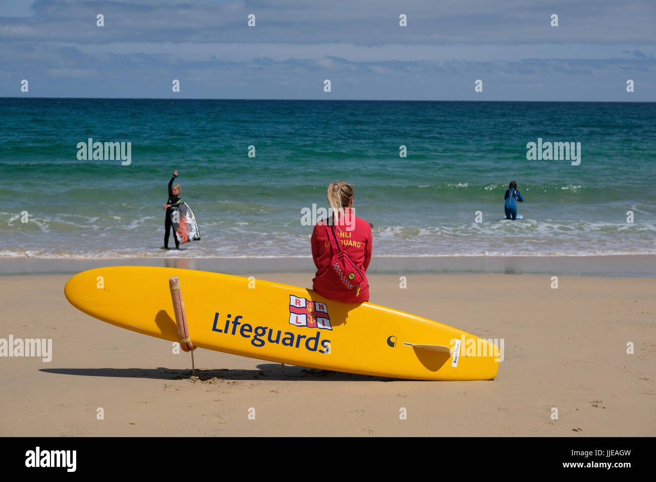 Giovani femmine bagnino guardando il mare sulla spiaggia di Carbis Bay vicino a St Ives, Cornwall Foto Stock