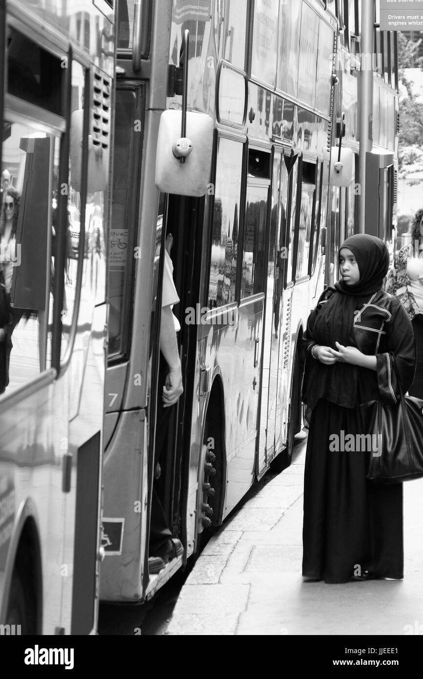 Una giovane donna musulmana sembra avere problemi gettng su un bus di Londra Foto Stock