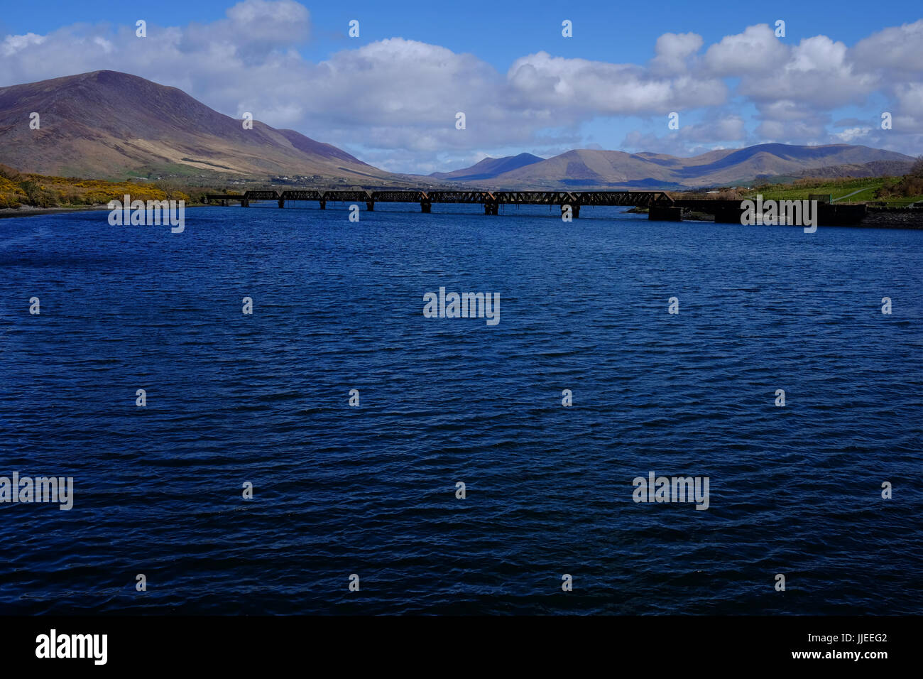 Il fiume Fertha e il ferro in disuso il ponte ferroviario di fronte alle montagne in Cahirsiveen, nella contea di Kerry, Irlanda Foto Stock