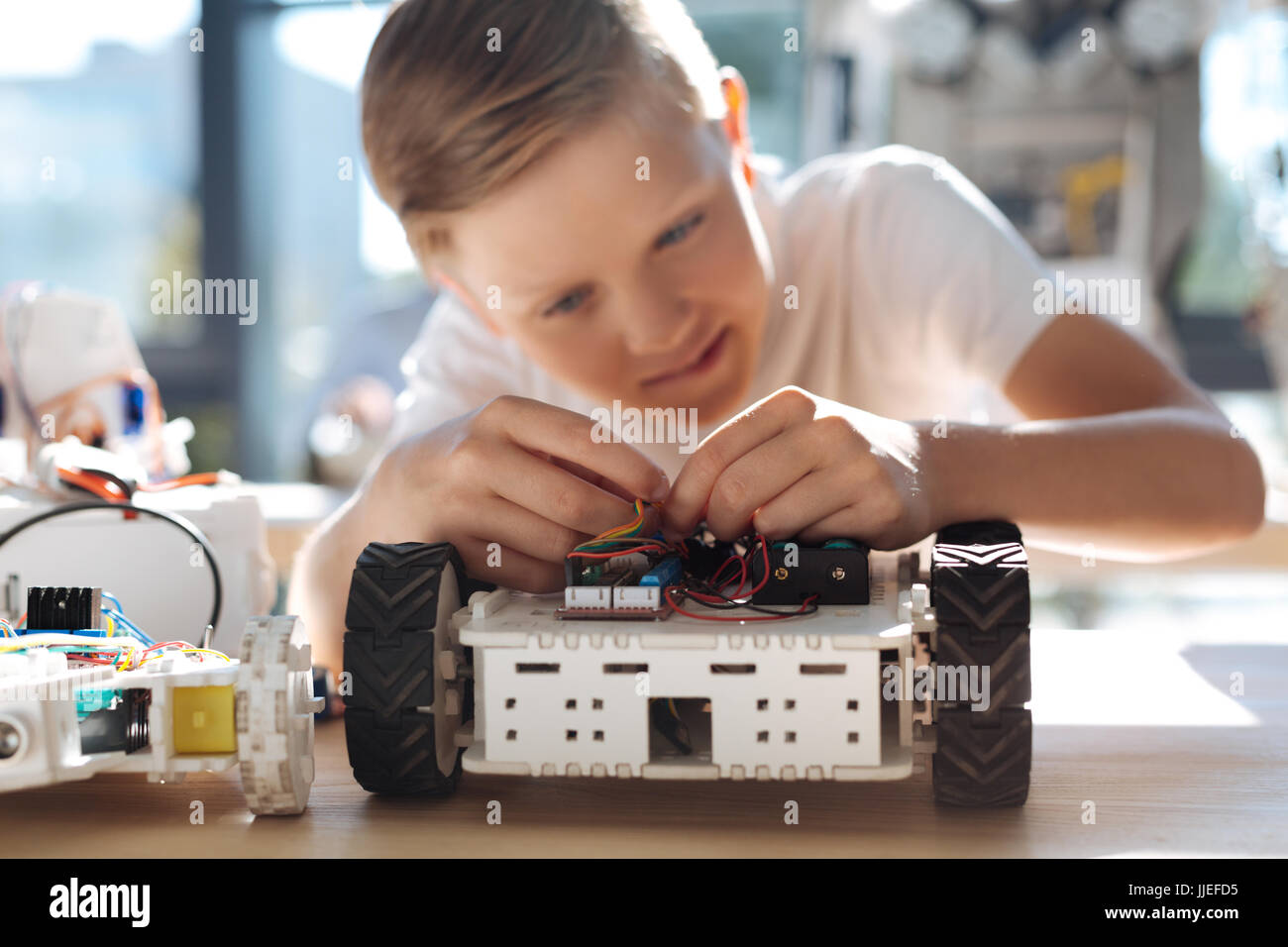 Ragazzo piacevole il collegamento dei fili nel veicolo robotico Foto Stock
