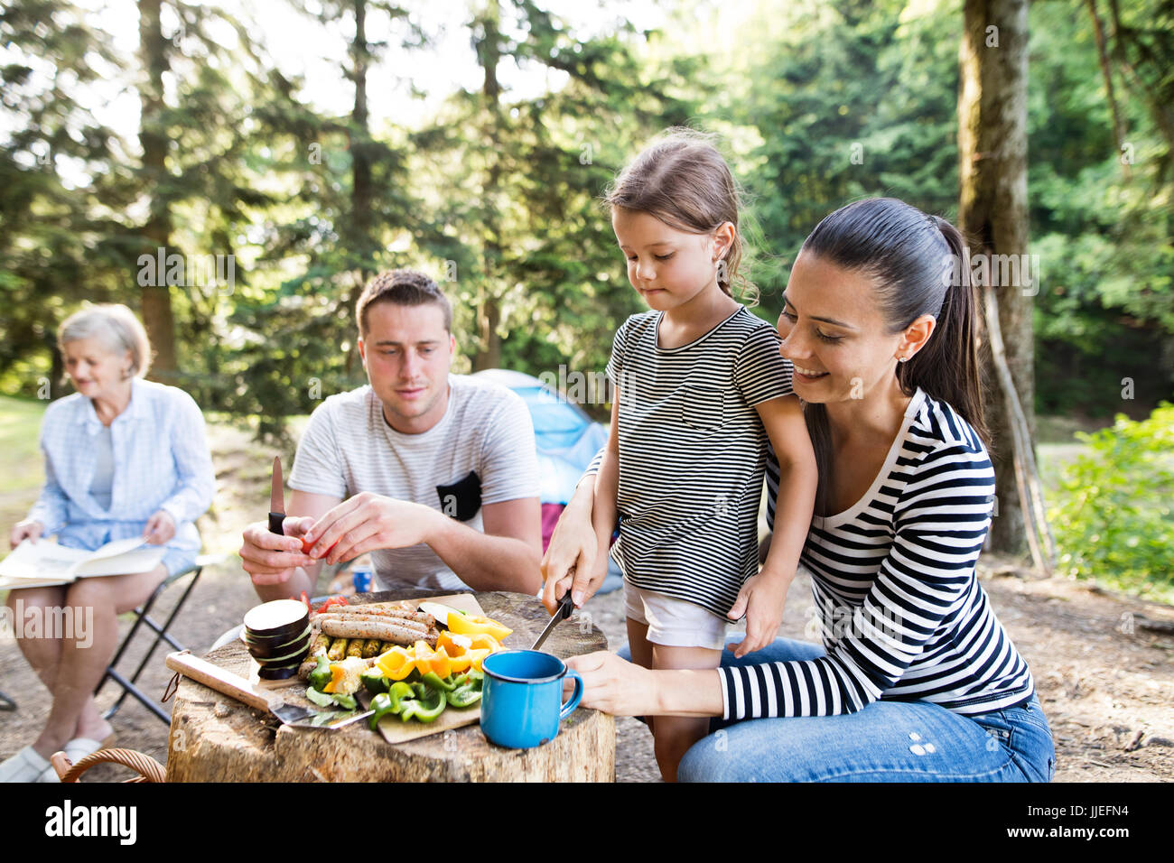 Bella famiglia campeggio in foresta, mangiare insieme. Foto Stock