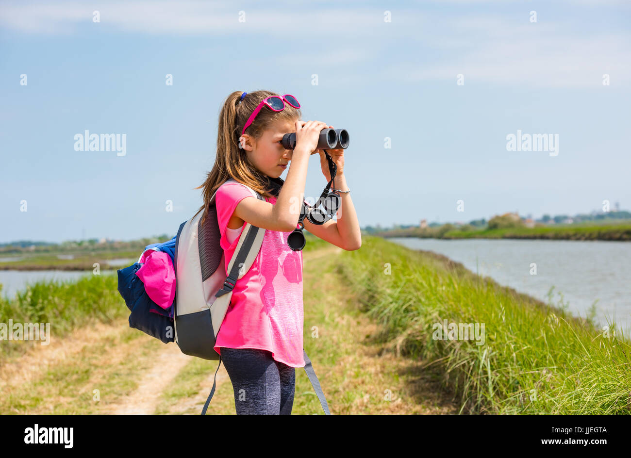 Giovane ragazza a guardare il parco attraverso il binocolo Foto Stock