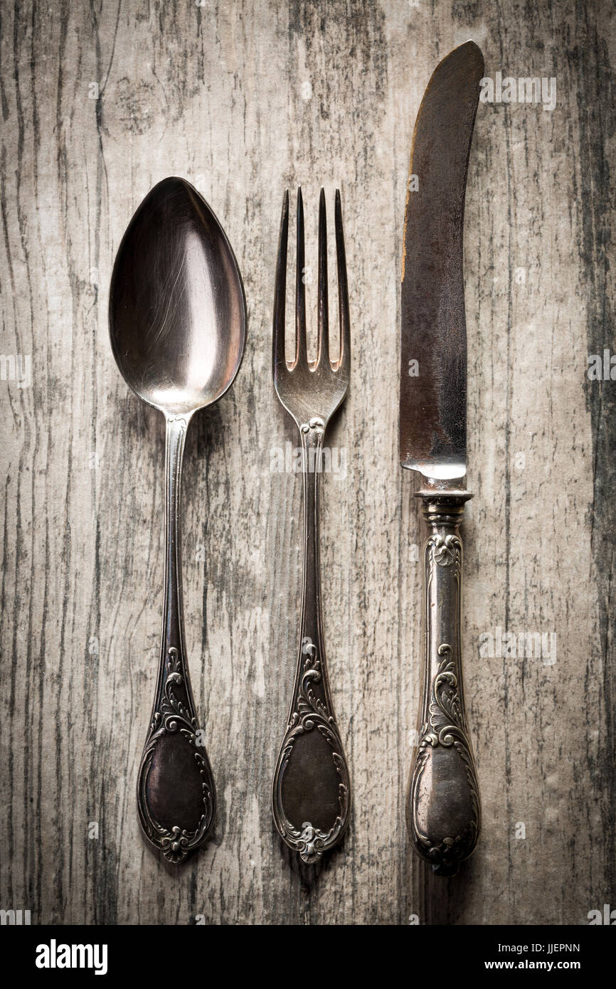 Antica cucchiaio, coltello e forchetta in legno scuro dello sfondo. Foto Stock