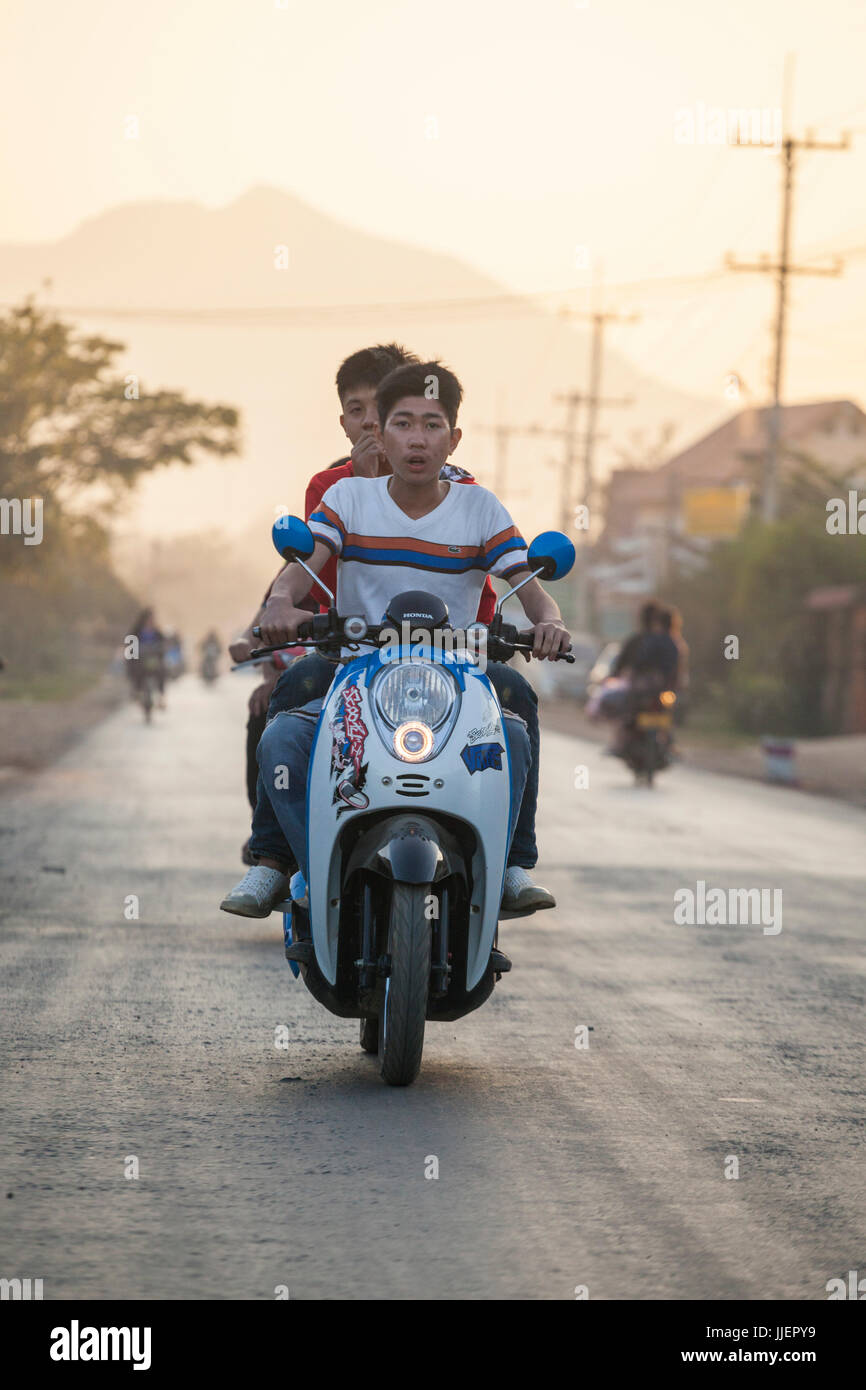 Giovani uomini ride insieme su uno scooter a motore al tramonto a Luang Prabang, Laos. Foto Stock