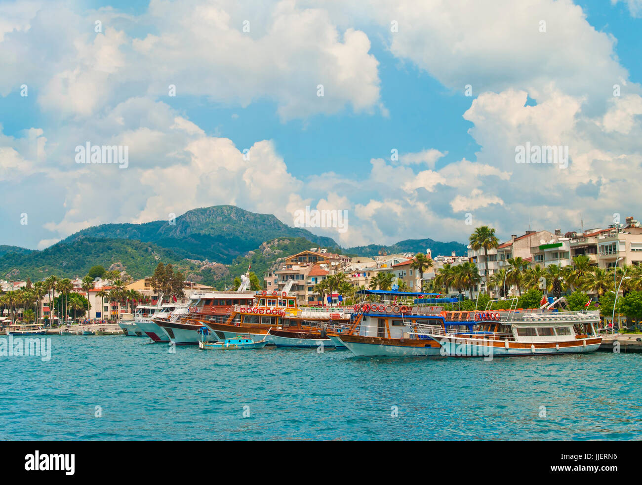 Vista delle imbarcazioni turistiche a Marmaris waterfront promenade sulla soleggiata giornata estiva con il blu del cielo e le montagne a sfondo, Turchia Foto Stock