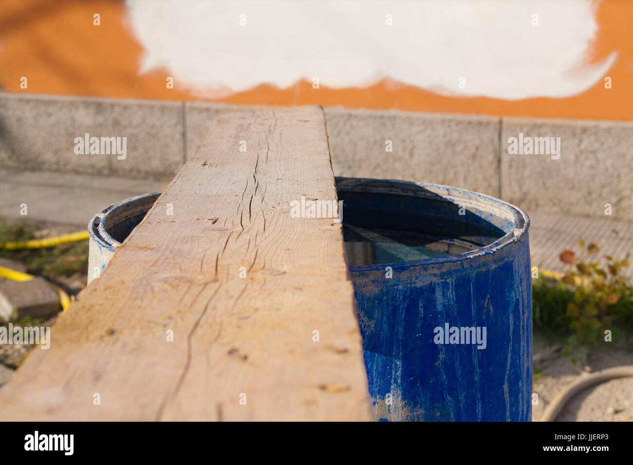 Albero di legno su blu di plastica riempito di acqua la canna nel sito in costruzione in Italia con i colori dei tubi di plastica sullo sfondo e rosso e bianco e a parete Foto Stock