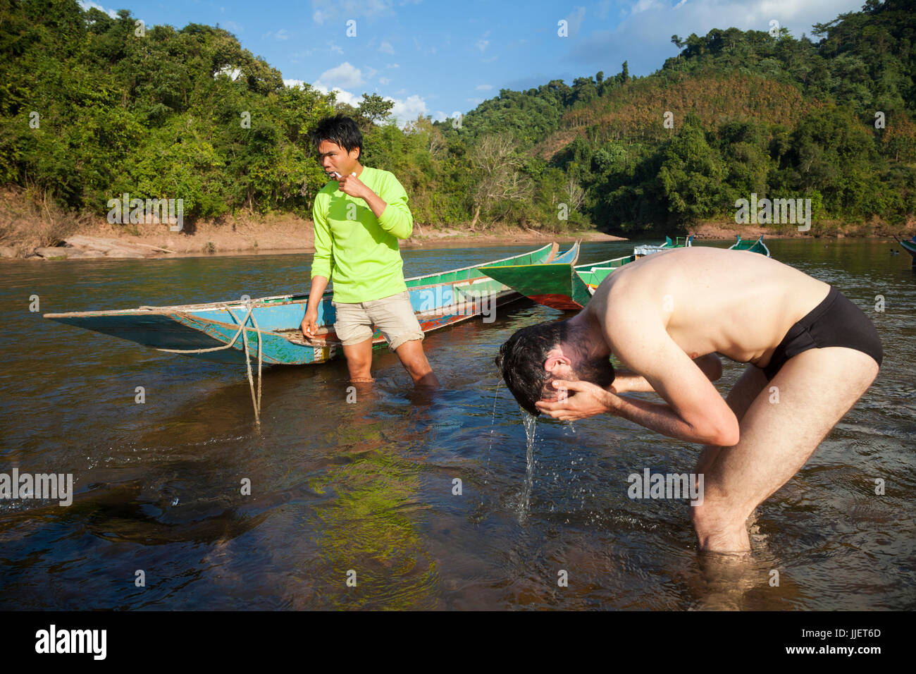 Mung (sinistra) e Robert Hahn spazzolare i denti e bagnarsi nel fiume Nam Ou fuori Muang Hat Hin, Laos. Foto Stock