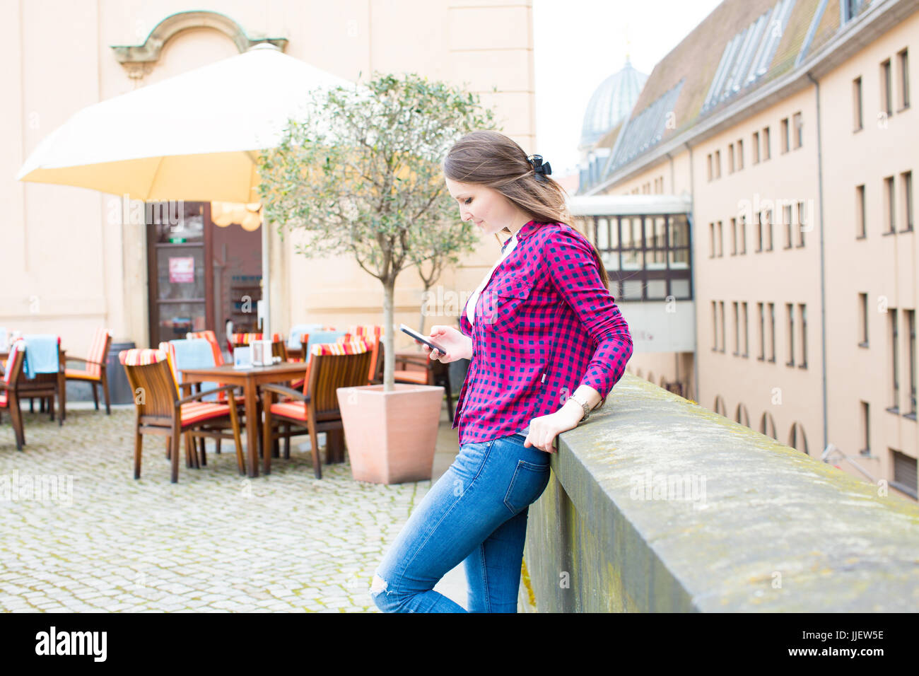 Ragazza utilizza lo smartphone nella vecchia città europea a sunny mattinata estiva Foto Stock