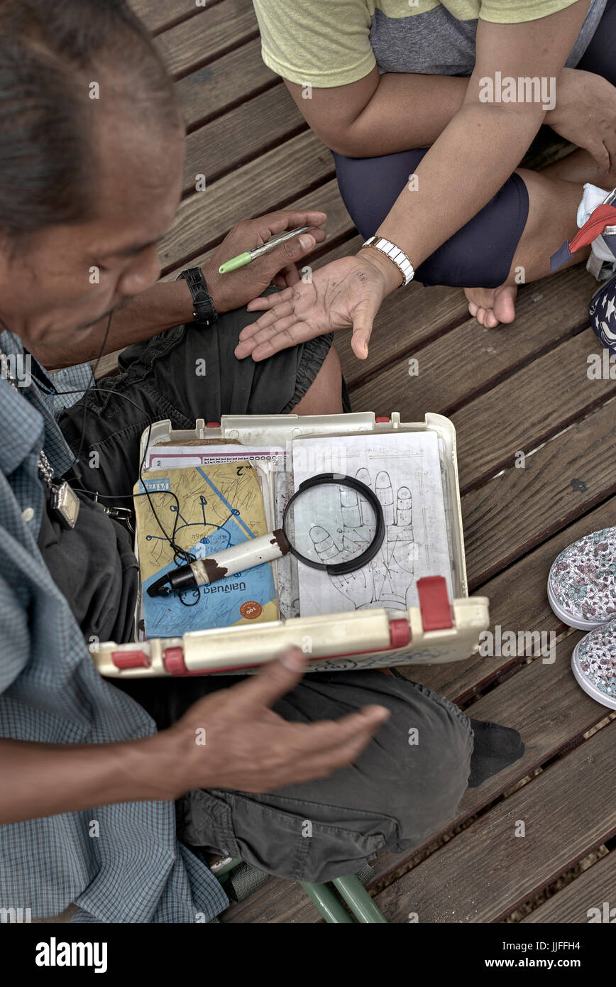 Lettore Palm fortuna teller con attrezzatura. Thailandia Sud-est asiatico Foto Stock