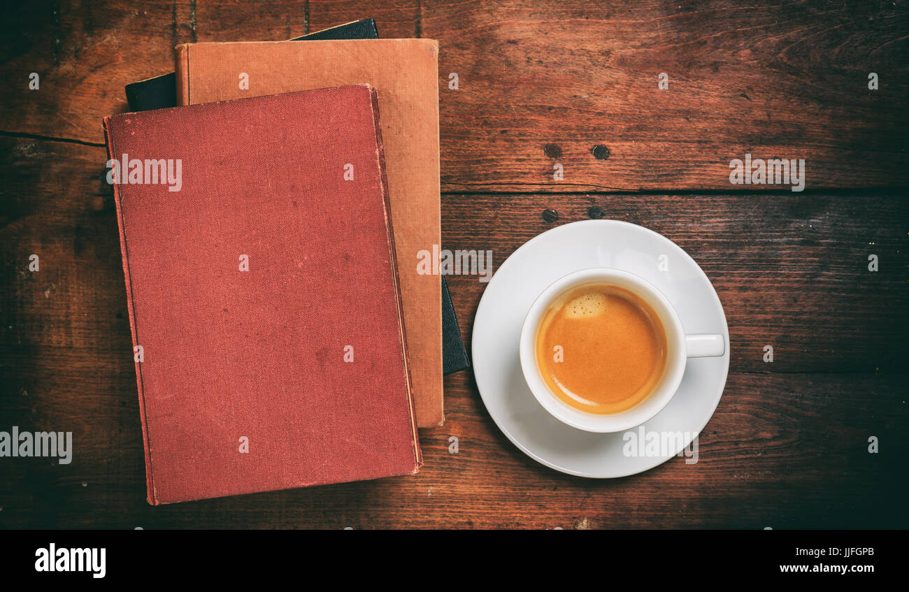 Libri antichi e una tazza di caffè su sfondo di legno Foto Stock