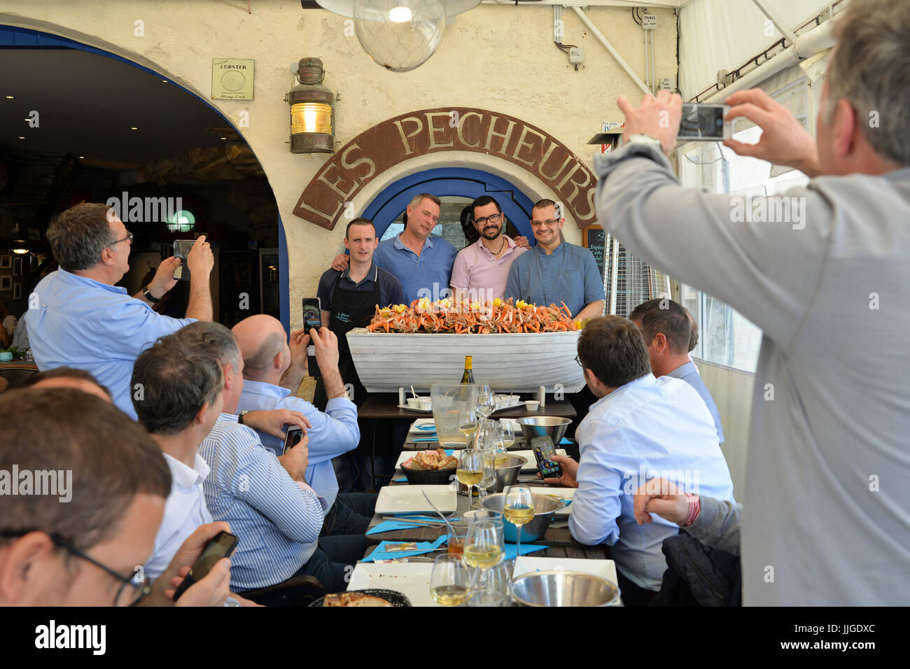 Gli scommettitori di scattare foto di chef che hanno consegnato un boatful di piatti a base di frutti di mare a tavola Foto Stock