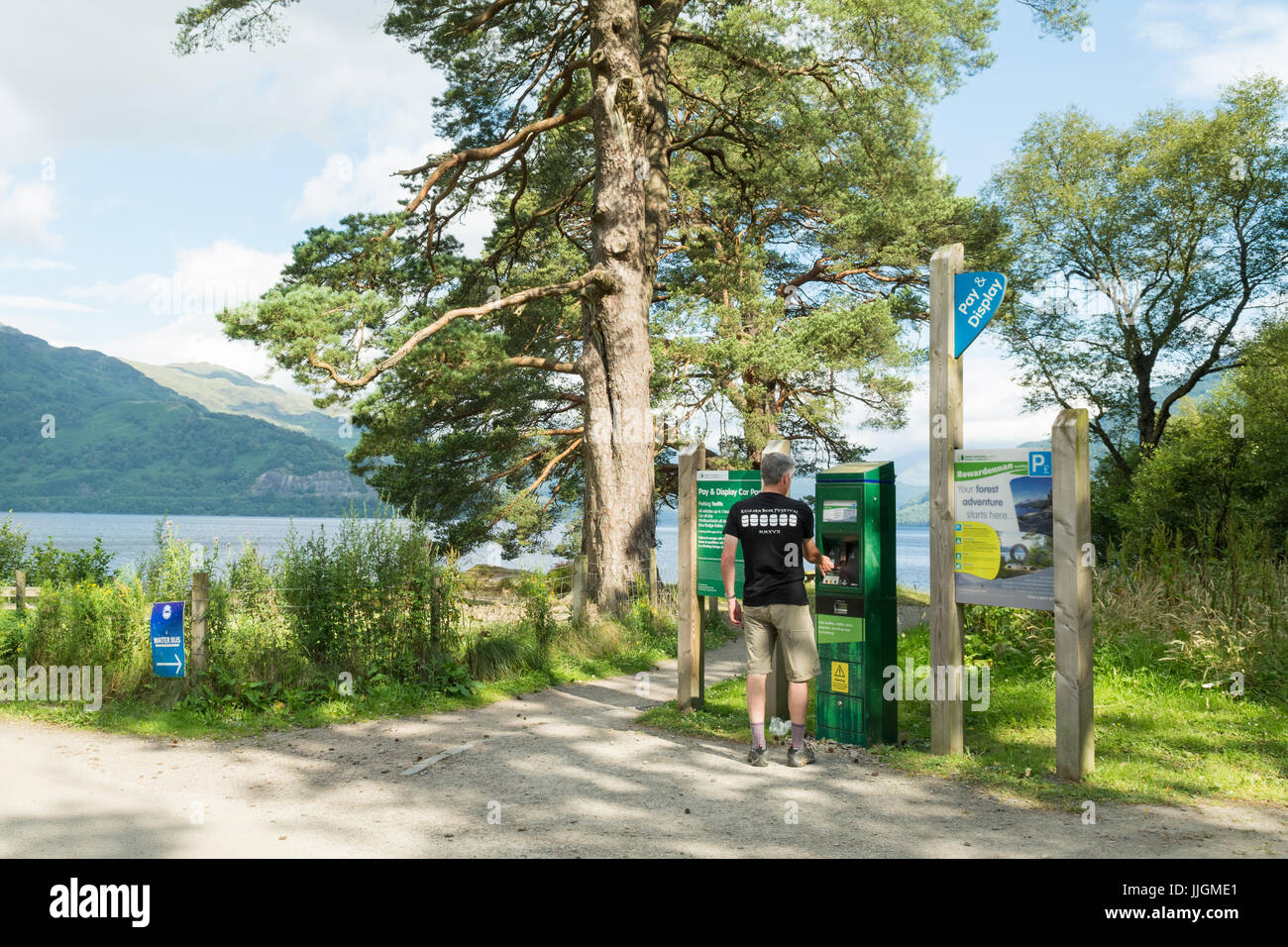 Uomo che paga a pagamento e mostra parcheggio a Rowardennan, Loch Lomond e Trossachs National Park, Scozia, Regno Unito Foto Stock