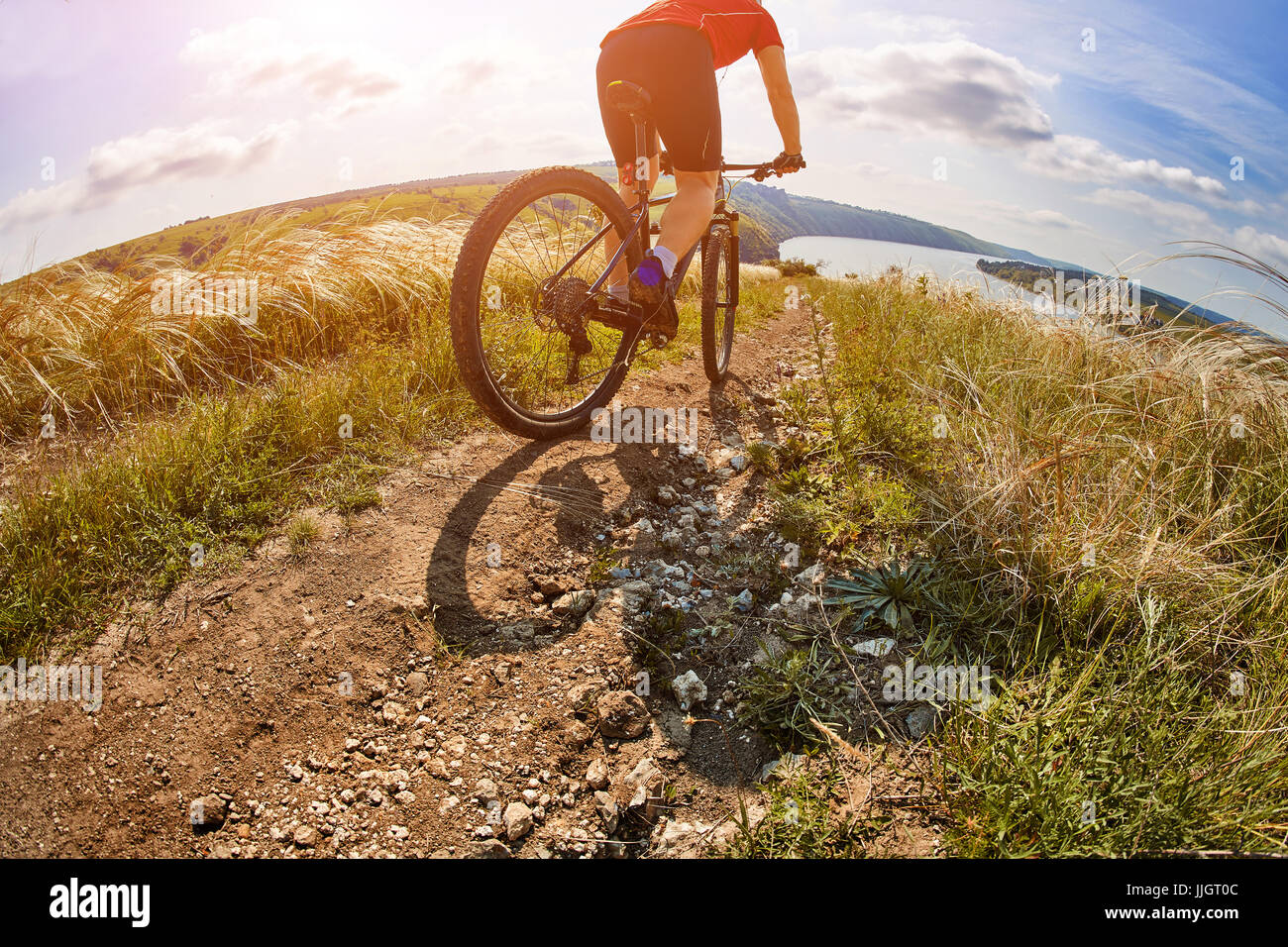 Avventura in mountain bike sul lungofiume. Viaggiatore con zaino cavalca la sua bicicletta in montagna. Foto Stock