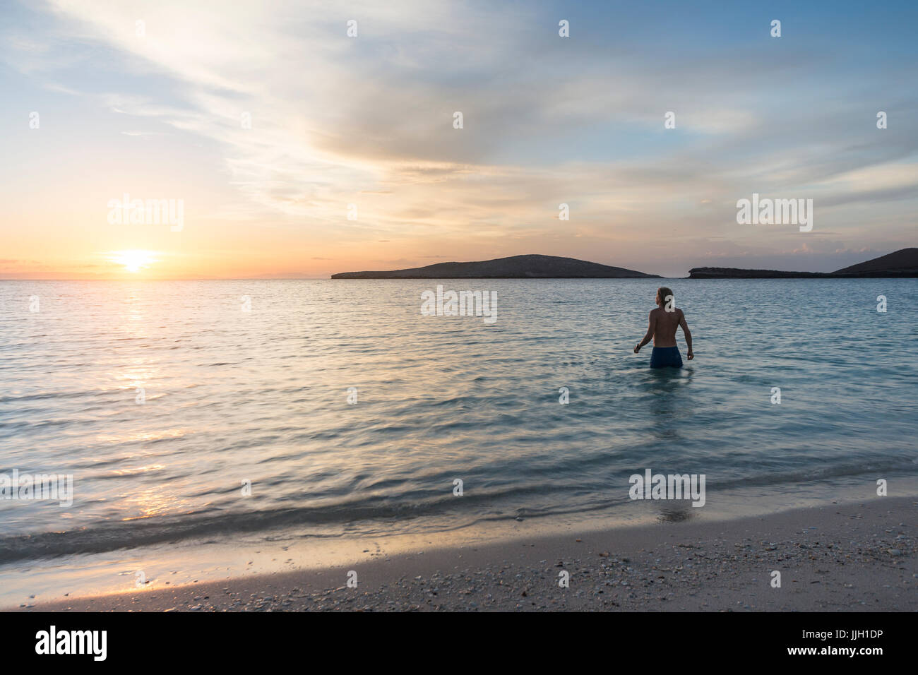 Un uomo guarda il sole che tramonta nel sereno mare di Cortez. Foto Stock