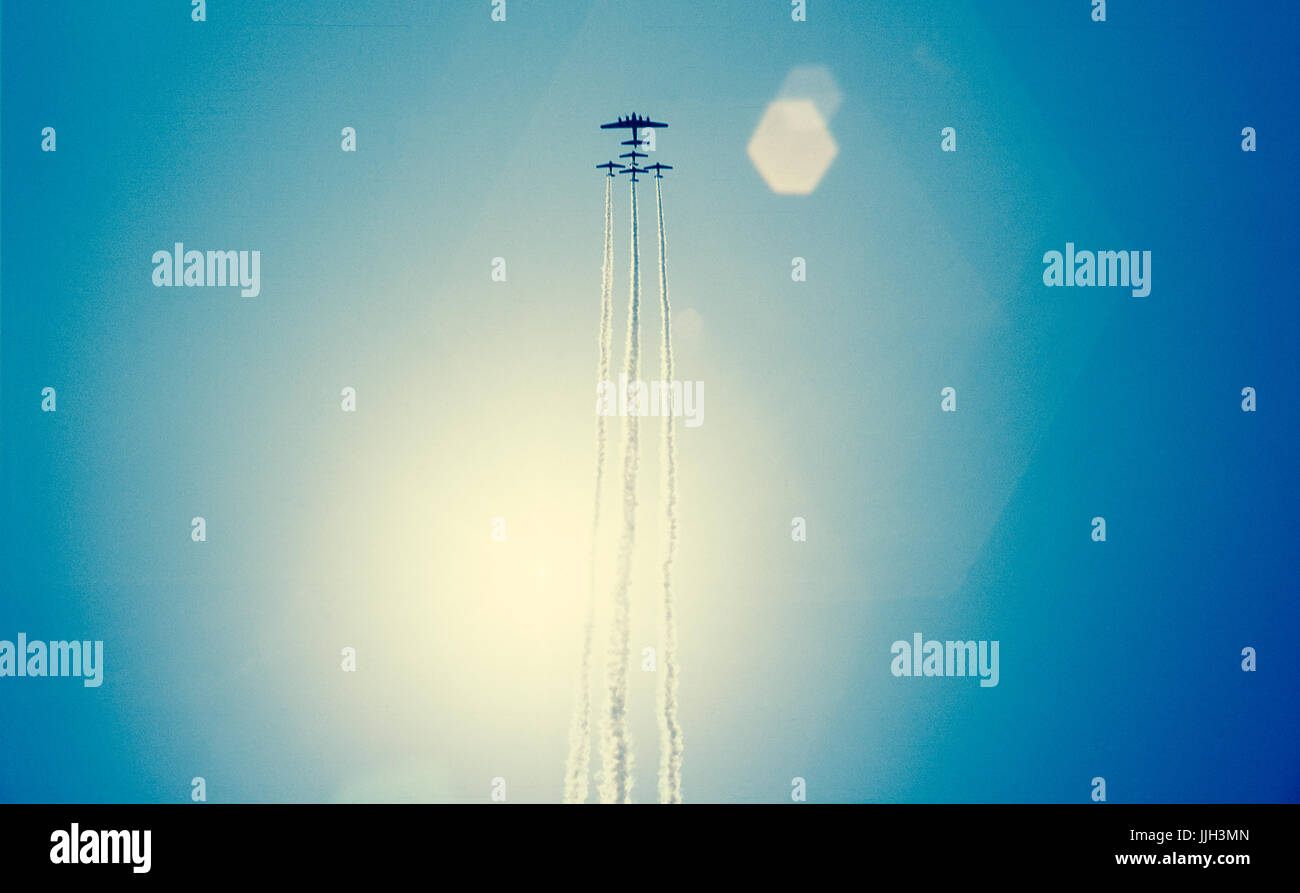 Cinque bomber vintage dagli aerei da guerra volare in formazione attraversando il sole, durante un air show, provocando gravi fotocamera lens flare. Foto Stock