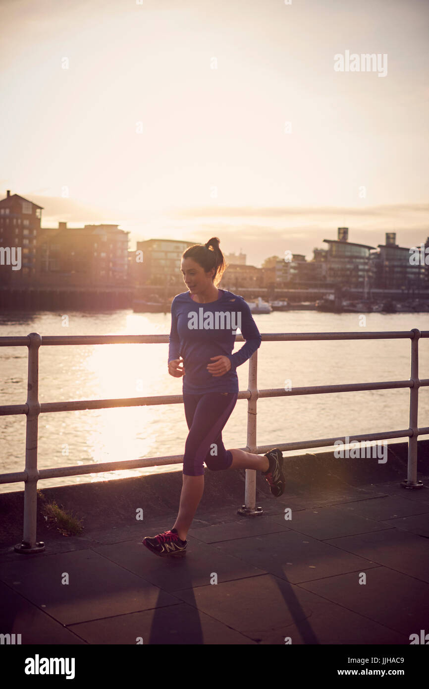 Una donna che costeggia il fiume Tamigi a Londra. Foto Stock