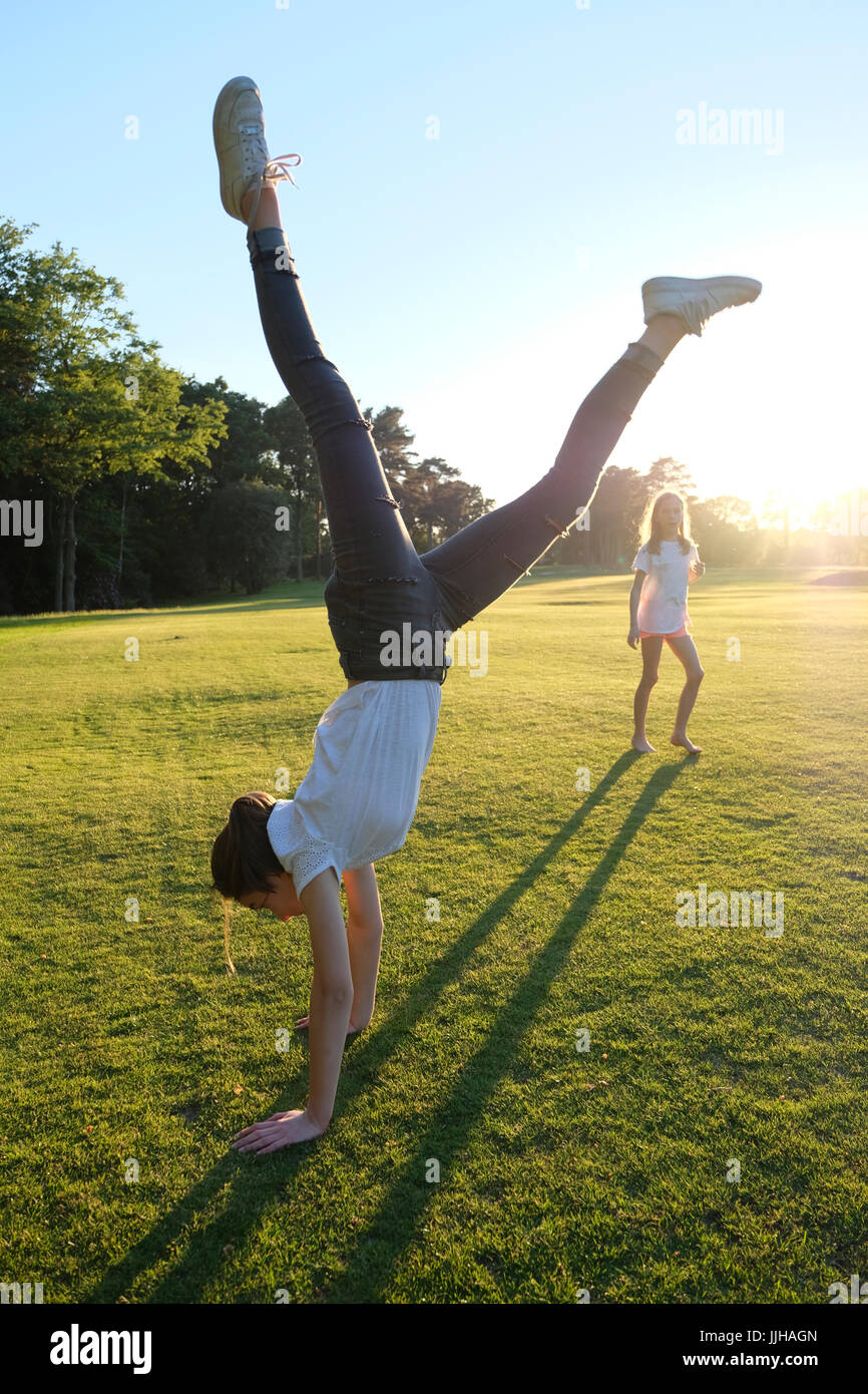 Una ragazza adolescente facendo un handstand guardato da sua sorella. Foto Stock