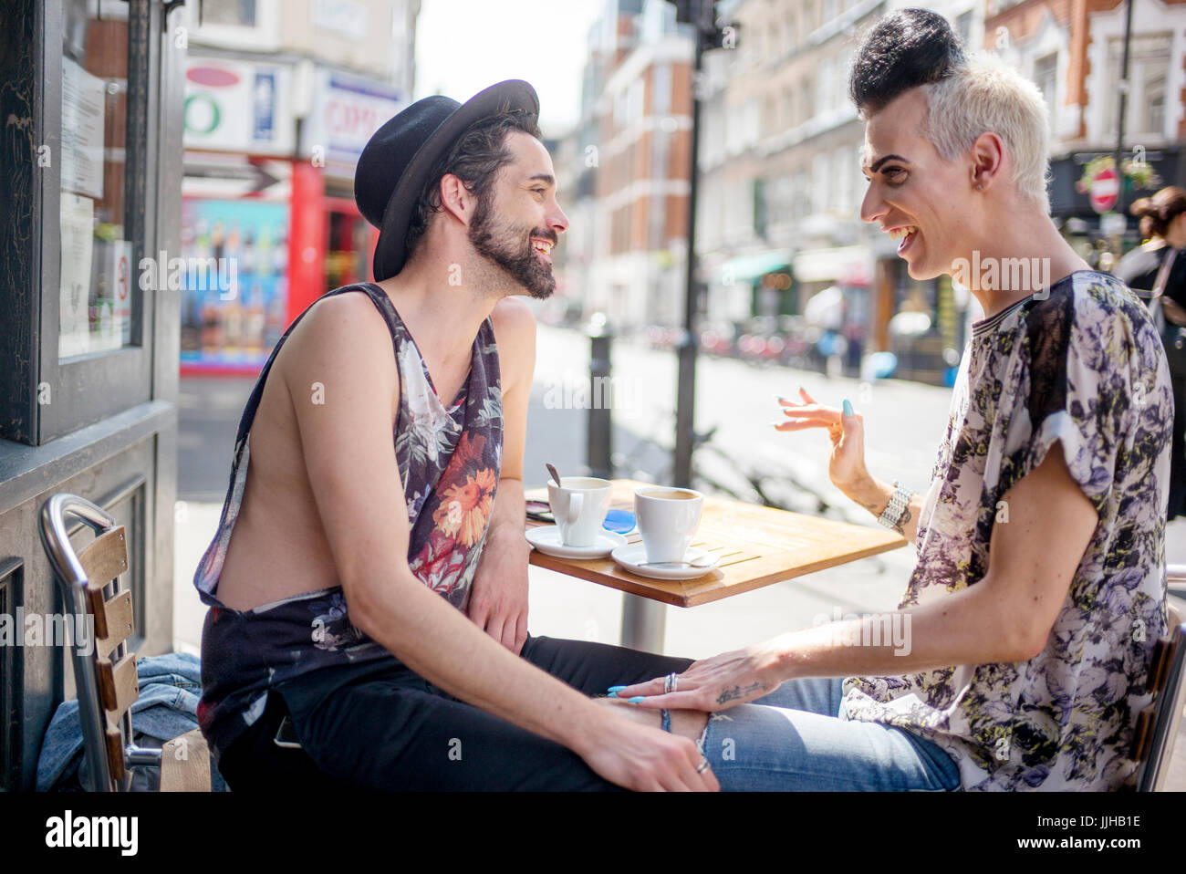 Una coppia gay chat al di fuori di un coffee shop a Londra. Foto Stock
