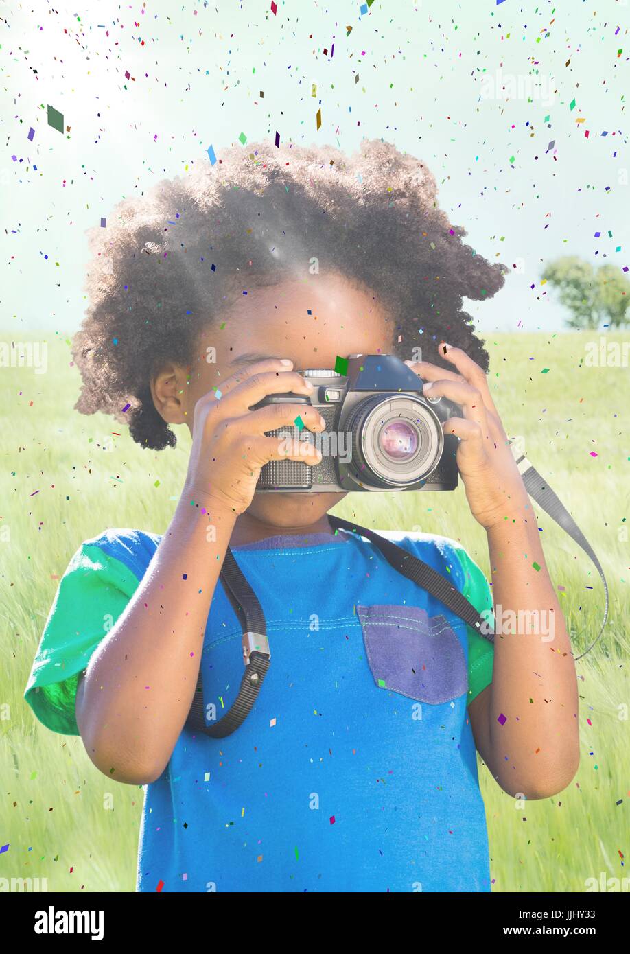 Ragazzo con fotocamera contro prato con la svasatura e coriandoli Foto Stock