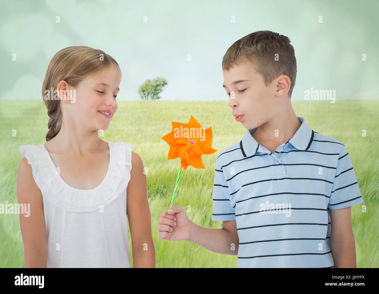 3d un ragazzo e una ragazza con il mulino a vento di giocattolo contro Prato Foto Stock