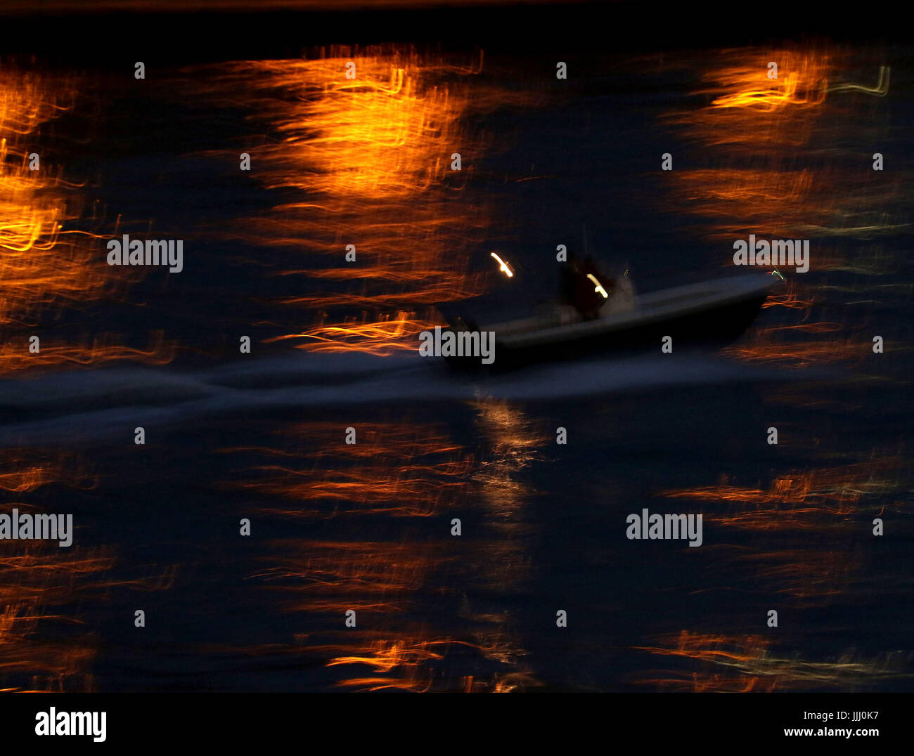 Barca con le luci della città che riflette sul fiume di notte Foto Stock