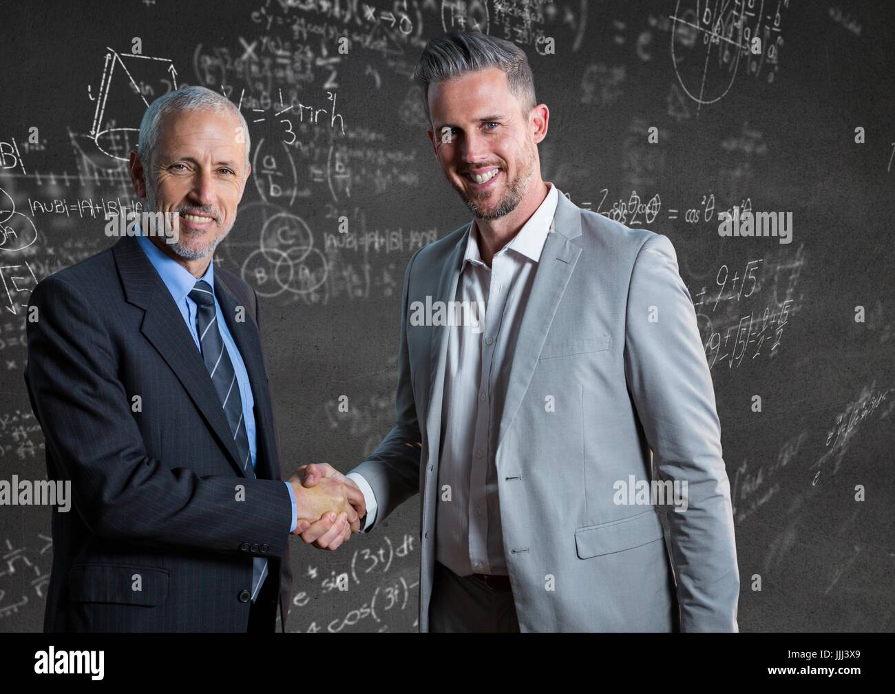 Gli uomini d' affari stringono le mani contro il muro grigio con math scarabocchi Foto Stock