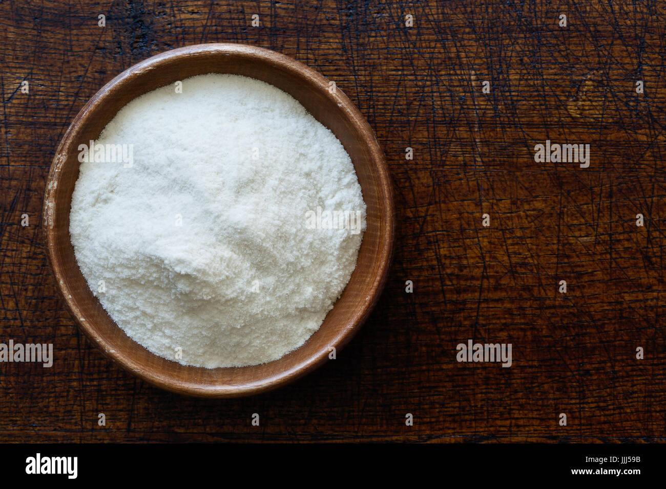 Farina di riso bianca in legno scuro ciotola isolato in legno marrone scuro dal di sopra. Foto Stock Farina di riso bianca in legno scuro ciotola isolato in legno marrone scuro dal di sopra. Foto Stock