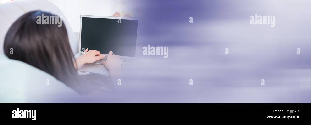 Donna sdraiata sul lettino digitando su laptop con sfocate transizione viola Foto Stock