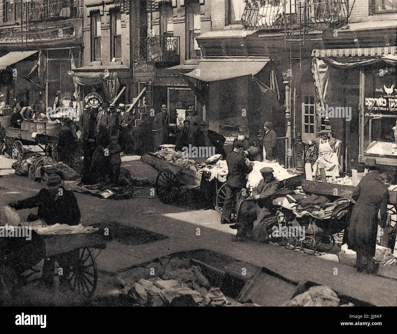 Lower East Side di New York, Stati Uniti d'America: strada del mercato nel quartiere ebraico che mostra con bancarelle e negozi con scrittura ebraica. Di barili al di fuori del negozio sul marciapiede marciapiede/. Pubblicato da Arthur Jaffé, Inc. La città di New York. Stampato da Max Jaffé, Vienna, Austria. Fotografo: F. H. Radowski. Foto Stock