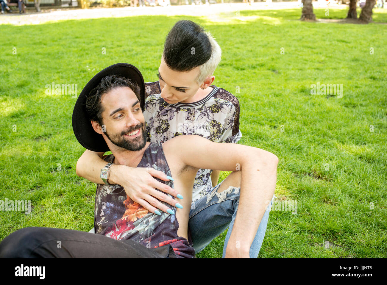 Una coppia gay godetevi il sole come essi rilassarsi nel parco. Foto Stock
