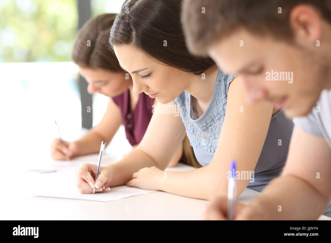 Close up di tre studenti di concentrato di fare un esame in aula Foto Stock