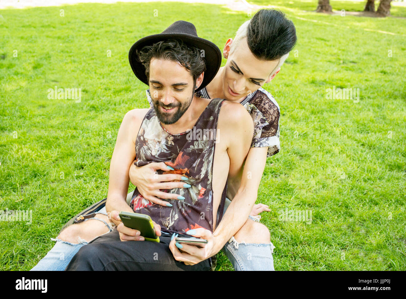 Una coppia gay godetevi il sole come essi rilassarsi nel parco. Foto Stock