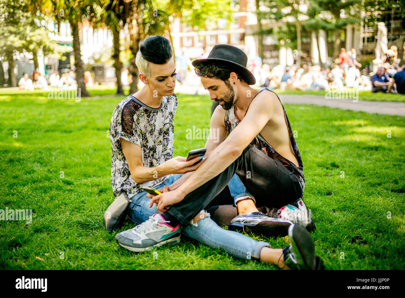 Una coppia gay godetevi il sole come essi rilassarsi nel parco. Foto Stock