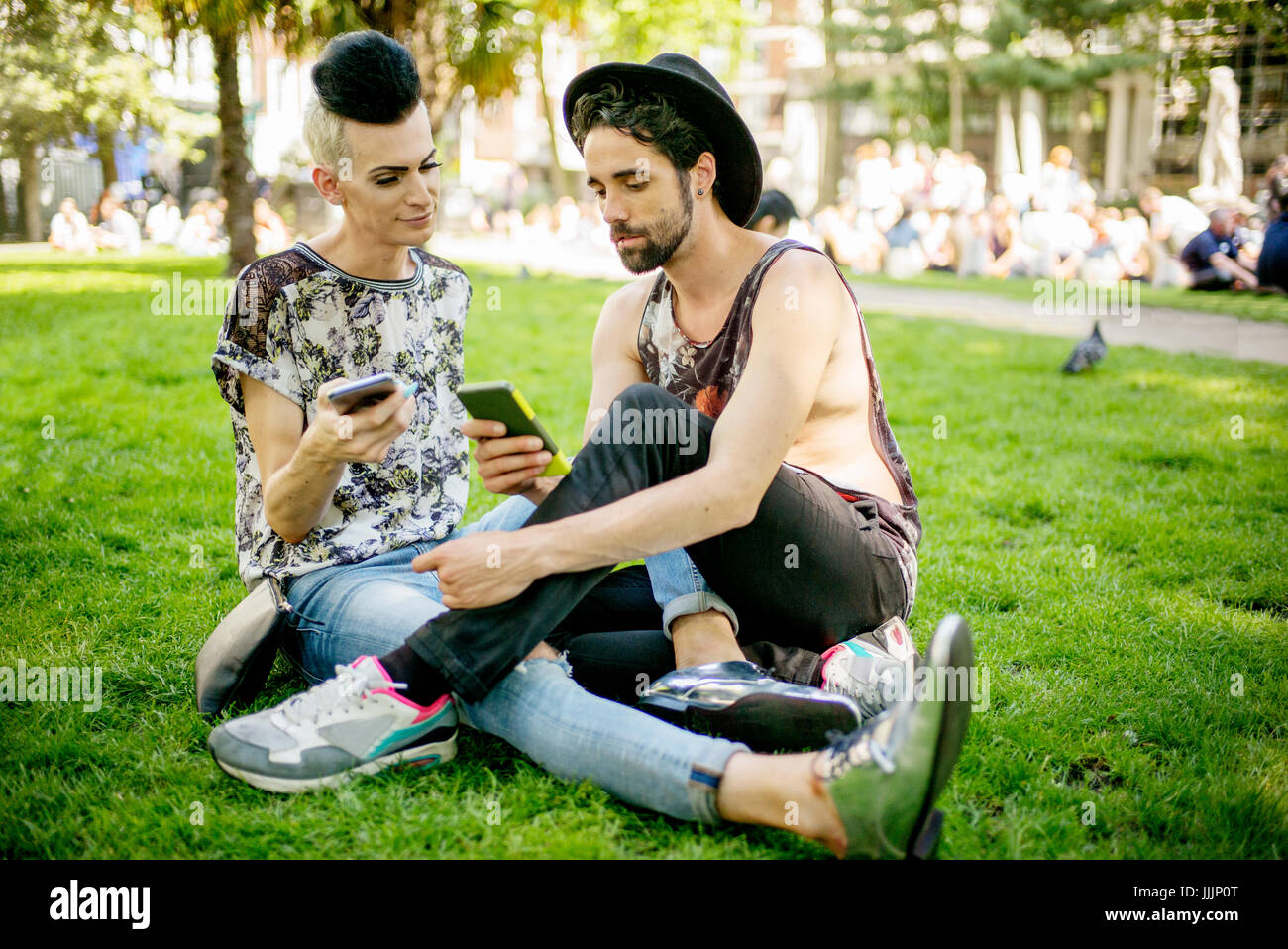 Una coppia gay godetevi il sole come essi rilassarsi nel parco. Foto Stock