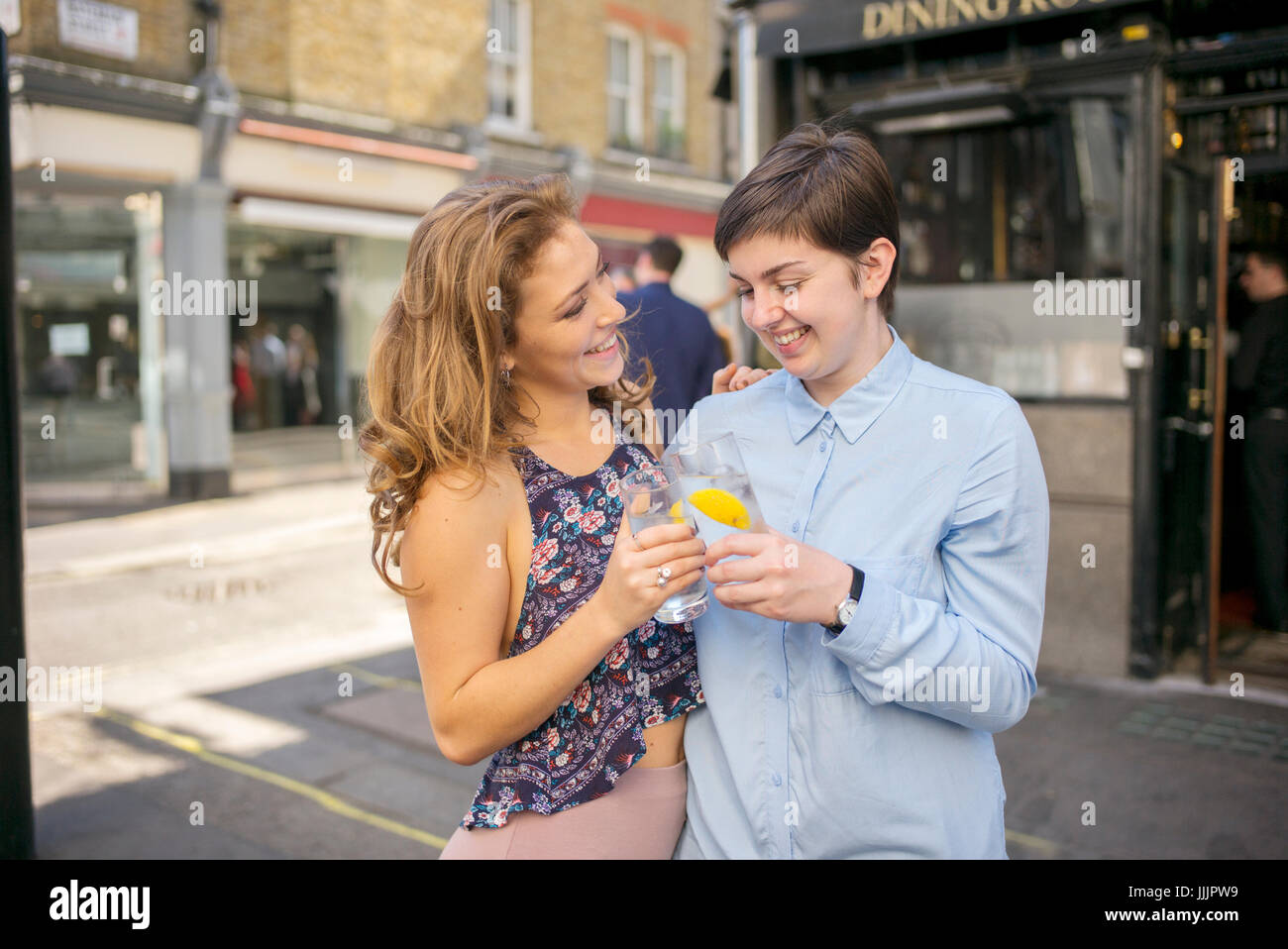 Una giovane coppia lesbica godetevi un drink al sole. Foto Stock