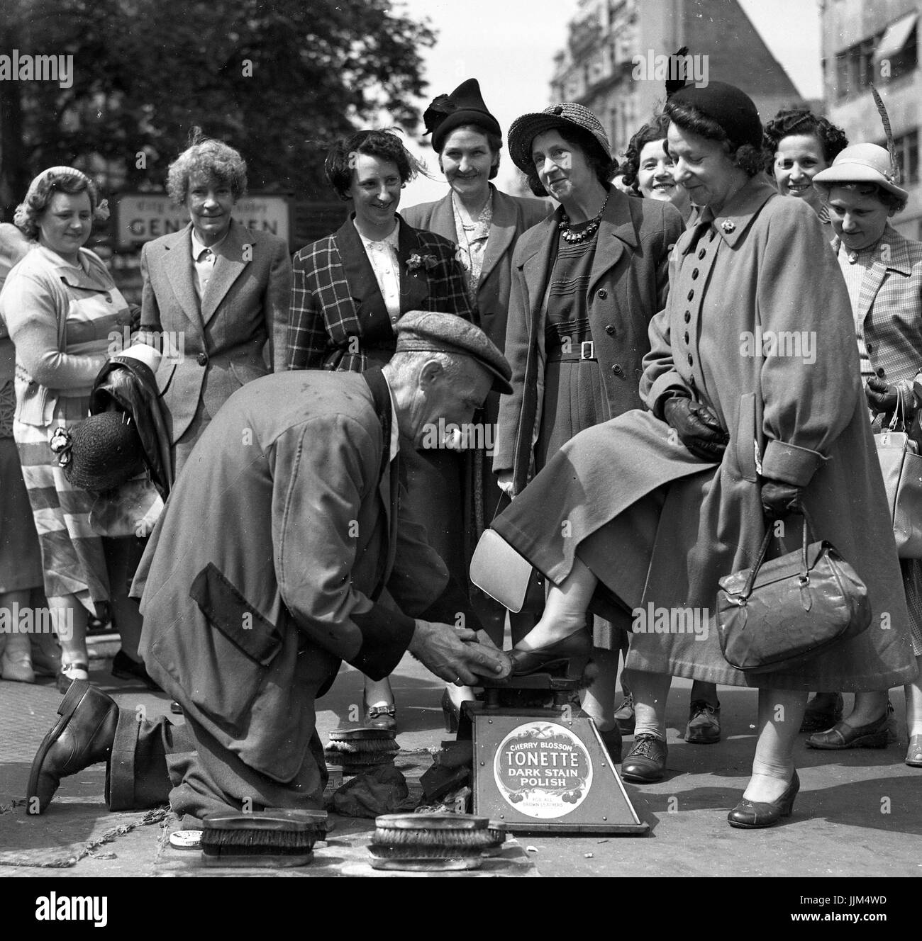 Disabilitato lustrascarpe uomo con una sola gamba lucidatura scarpe donna su un signore ragazze giorno in Londra 1949 il servizio di pulizia scarpe uomo Foto Stock