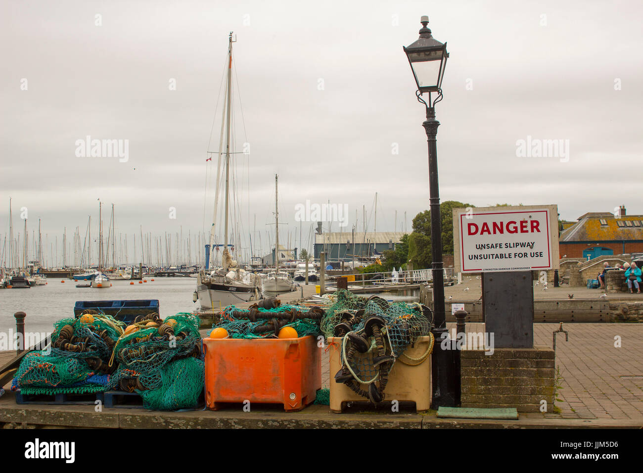 Commerciale di pesca reti memorizzate in una pila accanto a una inclinazione lampione sulla banchina a Lymington Harbour in Hampshire sulla costa sud dell'Inghilterra Foto Stock