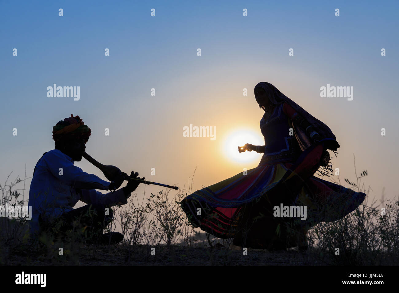 Silhouette di una donna gitana ballare una danza tradizionale alla musica di un musicista, Pushkar, Rajasthan, India Foto Stock