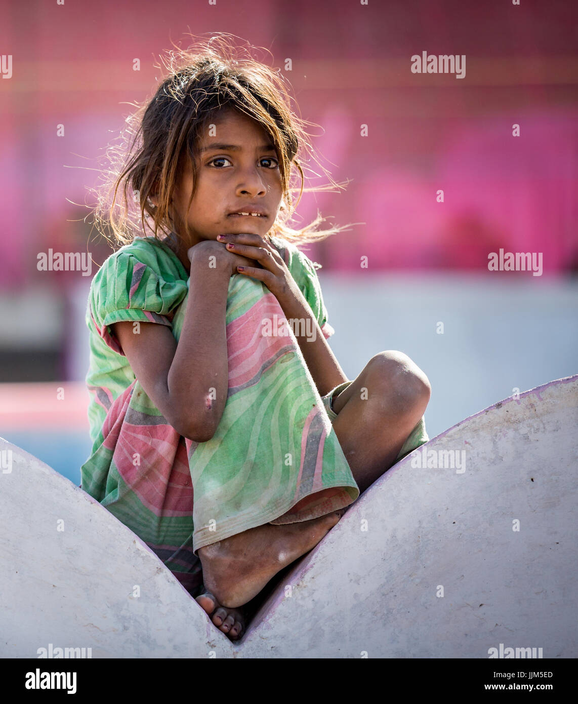 Poveri ragazza seduta su di una parete verticale, Pushkar, Rajasthan, India Foto Stock